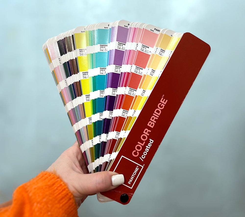 Hand holding color book swatches by Pantone